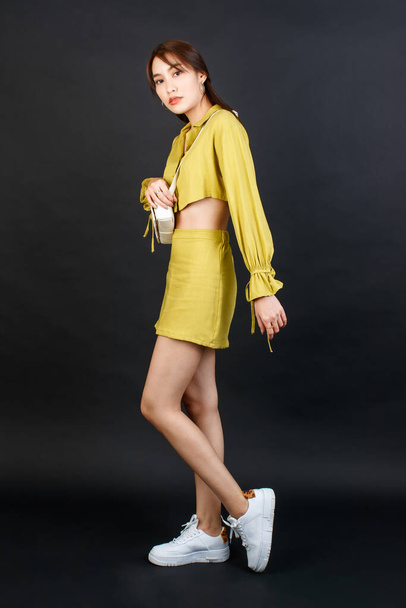 Portré stúdió lövés ázsiai városi divat női üzletasszony alkalmi növényi top ruhát cipelő táska táska, nézd meg a kamera fekete háttér. - Fotó, kép