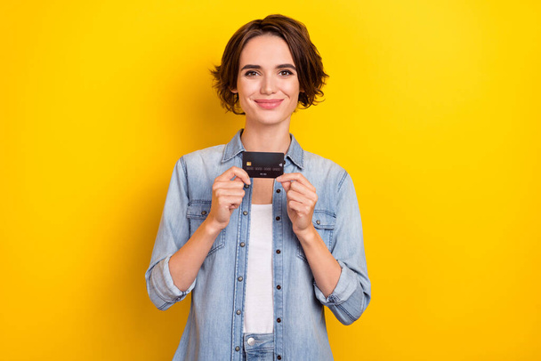 Photo of young pretty lady hold credit card income profit advertise promoter isolated over yellow color background - Fotografie, Obrázek