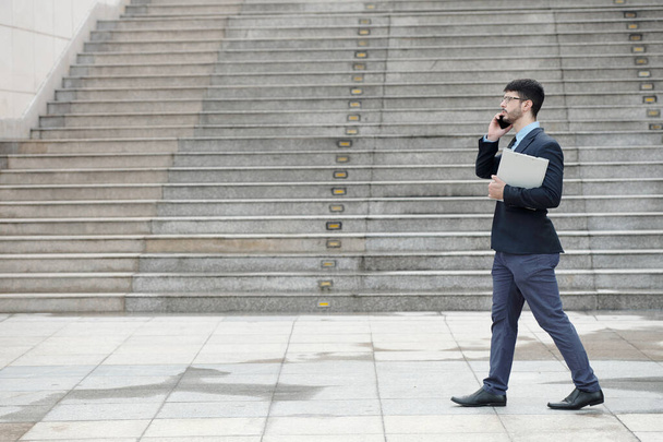 電話で話しているビジネスマンを歩く - 写真・画像