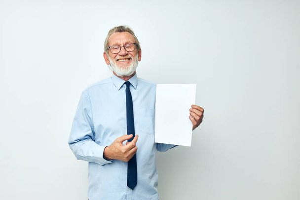 Portrait of happy senior man holding documents with a sheet of paper light background - Photo, Image