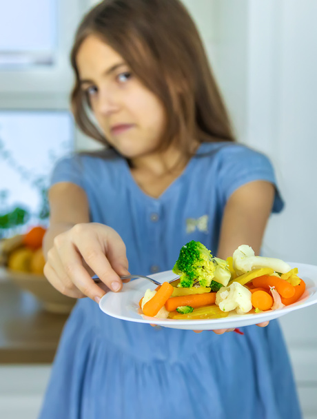 The child eats vegetables on a chair. Selective focus. - Photo, Image
