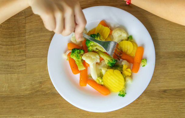 El niño come verduras en una silla. Enfoque selectivo. - Foto, Imagen