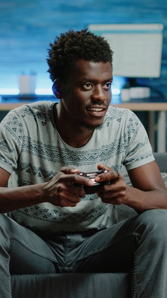 Uomo nero utilizzando controller e console per giocare ai videogiochi - Foto, immagini