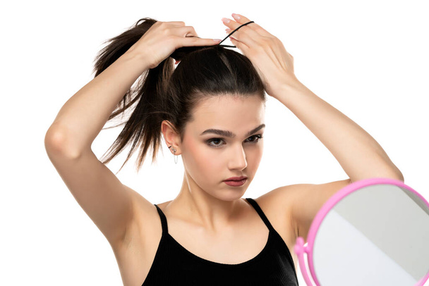 Frontr vista di una giovane donna legare i capelli lunghi su sfondo bianco - Foto, immagini