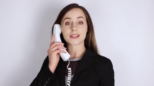 Μια νεαρή γυναίκα με ένα επαγγελματικό κοστούμι που απαντά στο τηλέφωνο και φλερτάρει ρομαντικά στο τηλέφωνο γραφείο ρομαντική έννοια - Πλάνα, βίντεο