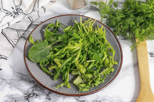 Rinse the arugula in water and cut the stems. Shake off excess moisture and place greens on a plate. - Fotografie, Obrázek