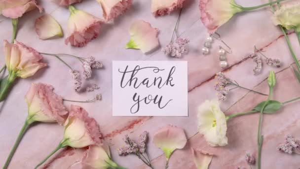 KÖSZÖNJÜK kártya egy márvány asztal közelében rózsaszín virágok tetejére nagyítás  - Felvétel, videó