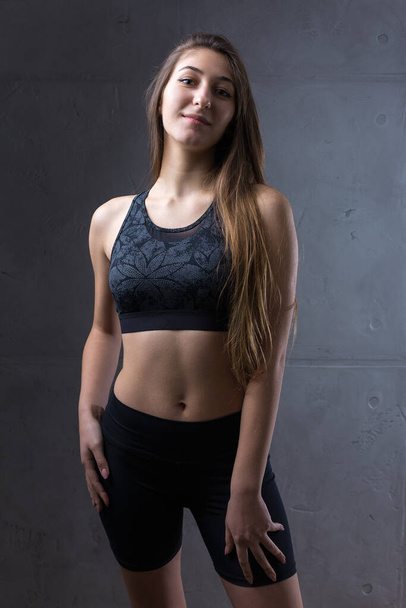Retrato de uma jovem atlética esbelta contra uma parede de concreto em um interior de apartamento na moda. - Foto, Imagem
