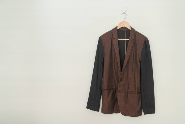 dark brown suit hanging with wood hanger on wall - Foto, imagen