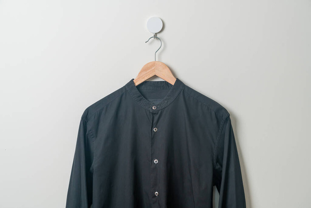 hanging black shirt with wood hanger on wall - Valokuva, kuva