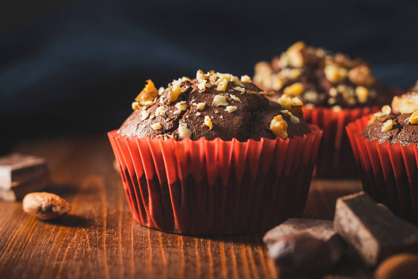 Homemade chocolate muffins or cupcakes sprinkled of nuts on a wooden board. - Foto, Imagen