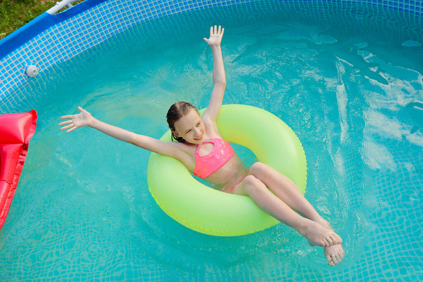 The girl happily swims in the pool in the summer. - Foto, Bild