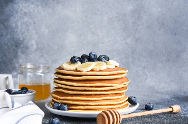 Homemade pancakes with syrup and berries. Morning and breakfast: pancakes with banana and blueberries. - Foto, afbeelding