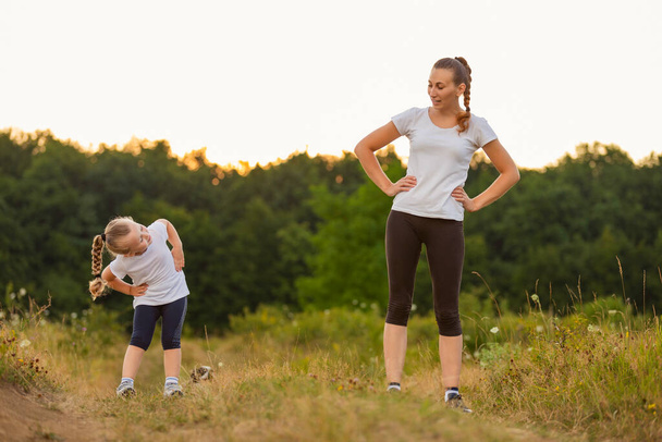 mom and daughter doing exercise in nature - Foto, imagen