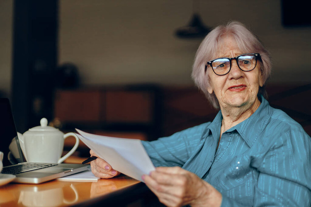 Portrait of an elderly woman documents work sheet of paper and pen unaltered - Fotó, kép