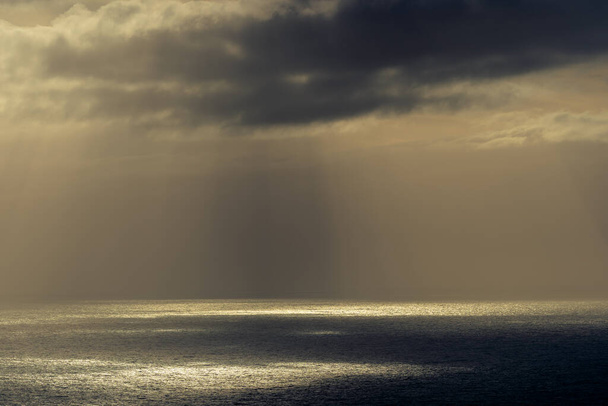 RUNDE, NORWEGIA - 2020 MAJ 06. Promienie słońca przez ciemne chmury w oceanie. - Zdjęcie, obraz