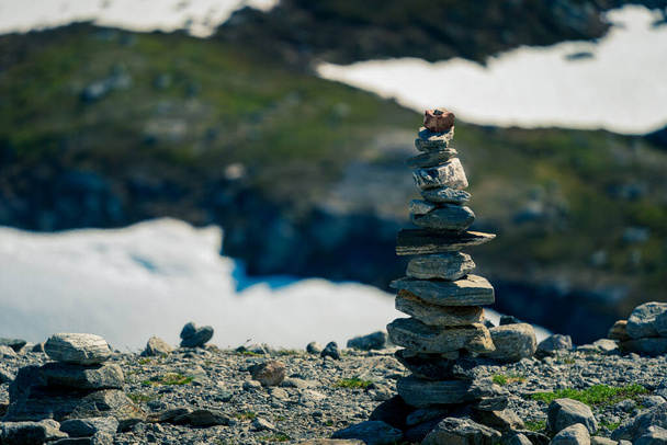TROLLSTIGEN, NORVÉG - 2020 Június 24. A kövek egyensúlyban vannak a sziklán. Folyami kövek piramisa egymásra.. - Fotó, kép