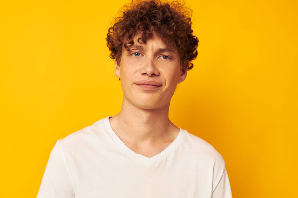 curly red-haired guy in a white t-shirt on a yellow background - Zdjęcie, obraz
