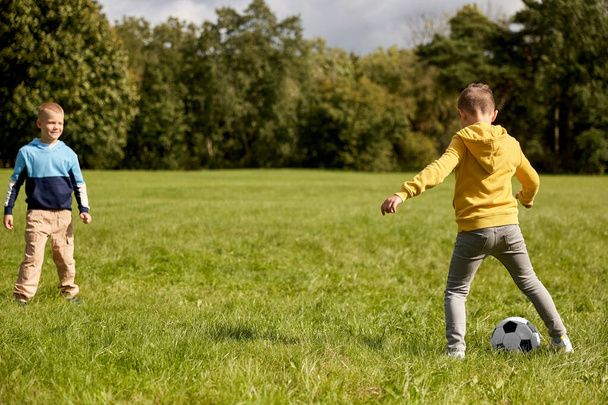 niños pequeños felices con pelota jugando al fútbol en el parque - Foto, imagen
