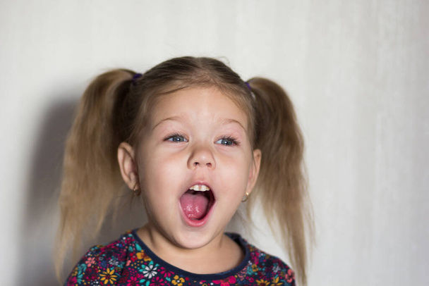 Portrait of funny happy caucasian of three age little girl with open mouth looking aside on the white background - Фото, изображение