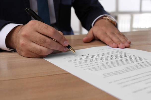 Businessman signing contract at wooden table indoors, closeup - Foto, immagini