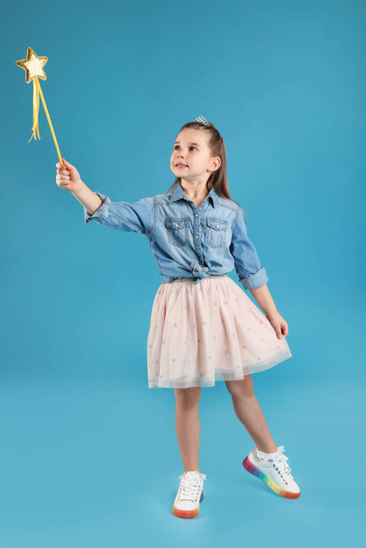 Cute girl in diadem with magic wand on light blue background. Little princess - Photo, image