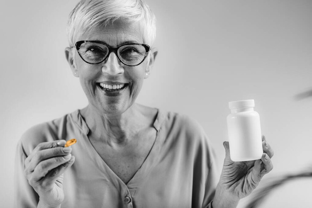 Femme âgée tenant la capsule et la bouteille de vitamine D. - Photo, image
