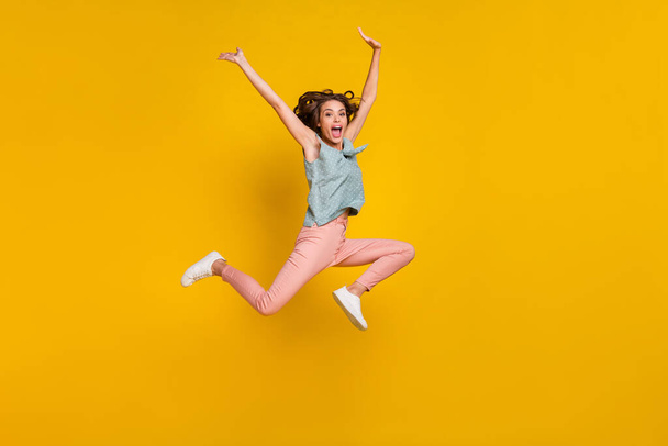 Full body photo of cheerful positive crazy woman jump up raise hands active isolated on yellow color background - Foto, afbeelding