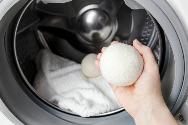 Mulher usando bolas de secador de lã para roupas mais macias enquanto seca na máquina de lavar roupa conceito. Descarregar eletricidade estática e encurtar o tempo de secagem, economizar energia. - Foto, Imagem