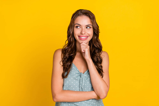 Photo of minded dreamy young woman hold hand chin look empty space idea isolated on yellow color background - Fotó, kép