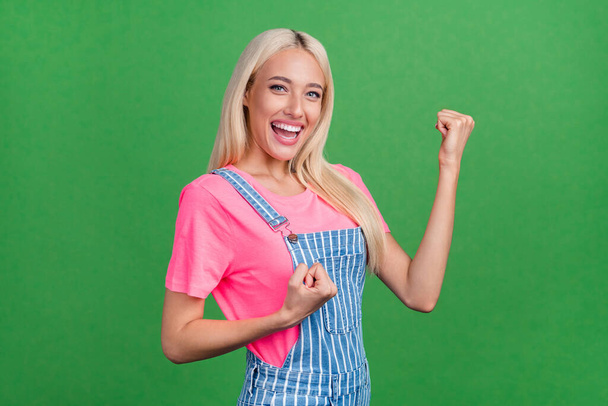 Photo of positive astonished lady celebrate victory rejoice triumph wear striped overall isolated green color background - Photo, image