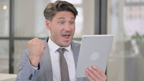 Middle Aged Man Celebrating on Tablet in Office - Photo, Image
