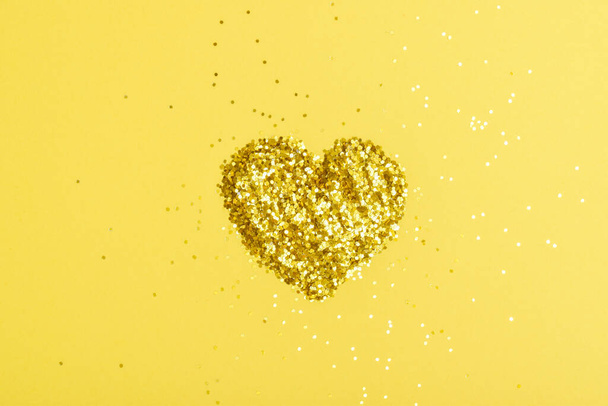 Yellow metal sequins are framed with a heart on a yellow background. - Фото, изображение