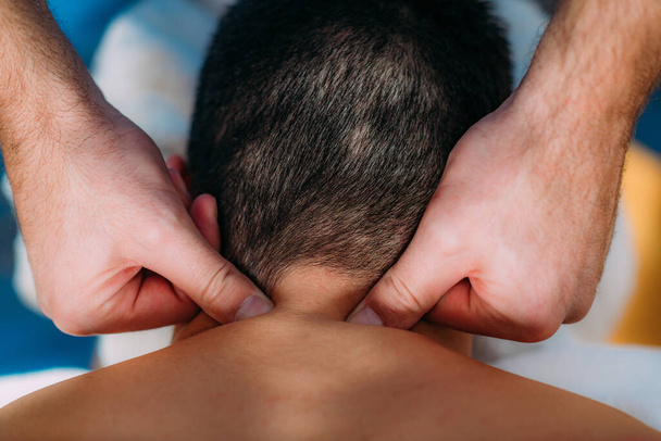 Physiotherapist massaging male patient with injured neck. Sports injury treatment. - Fotografie, Obrázek