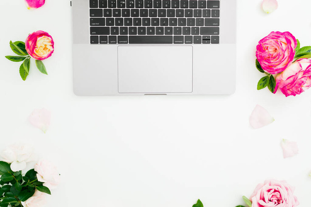 Laptop, rosas flores y pétalos sobre fondo blanco. Acostado. Vista superior
. - Foto, Imagen