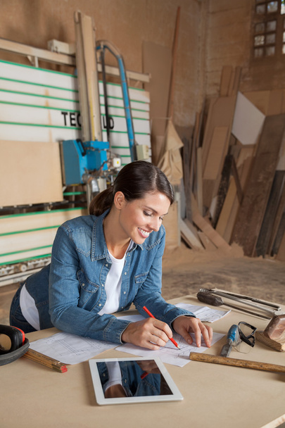 Female Carpenter Working On Blueprint In Workshop - Foto, Imagen