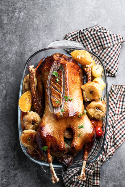 Baked  Christmas goose stuffed with apples served with baked vegetables on gray stone background  - Foto, Imagem