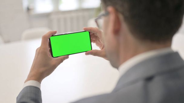 Hombre mirando Smartphone con pantalla de croma verde - Foto, Imagen