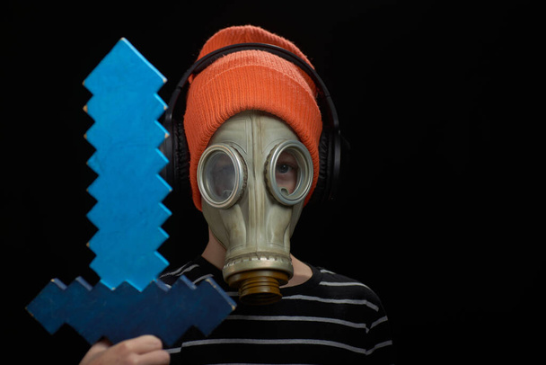 Portrait of a boy in a gas mask and a sword on a dark background - Foto, Imagen