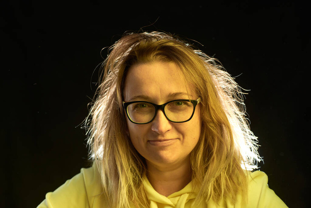 Adult woman in glasses with bad hair, on a dark background - Foto, Bild