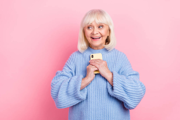 Portrait of attractive cheerful amazed grey-haired woman using device like post app isolated over pink pastel color background - Foto, immagini