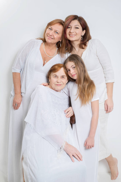 Soft group portrait of women of the same family of different generations in light clothes on a white background. - Фото, зображення