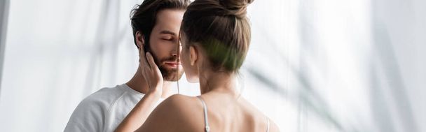 vue arrière de la femme embrassant homme barbu avec les yeux fermés à la maison, bannière - Photo, image