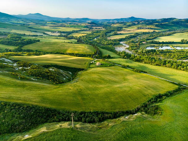 Superbe vue aérienne de champs verdoyants et de terres agricoles avec de petits villages à l'horizon. Paysage rural estival de collines, routes courbes et cyprès de Toscane, Italie. - Photo, image