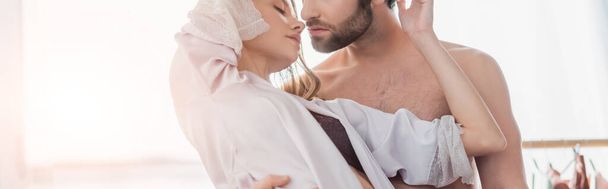 bearded man hugging young woman in silk robe, banner - 写真・画像
