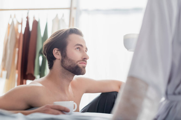 bearded man looking at woman in robe and holding cup  - Foto, Imagem