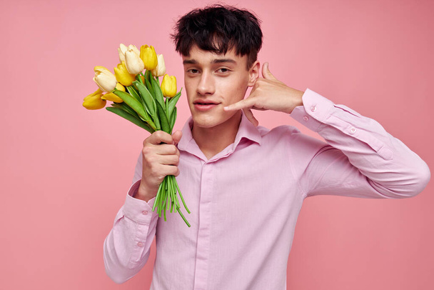 portrait of a young man bouquet of flowers date romance posing pink background unaltered - Foto, Imagen
