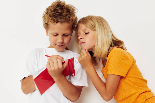 imagen de la diversión positiva del niño y de la muchacha en las camisetas coloridas con un fondo aislado del bloc de notas inalterado - Foto, imagen