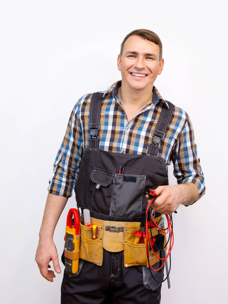 Happy technician in uniform over white background. Electrician with standard equipment - Photo, Image