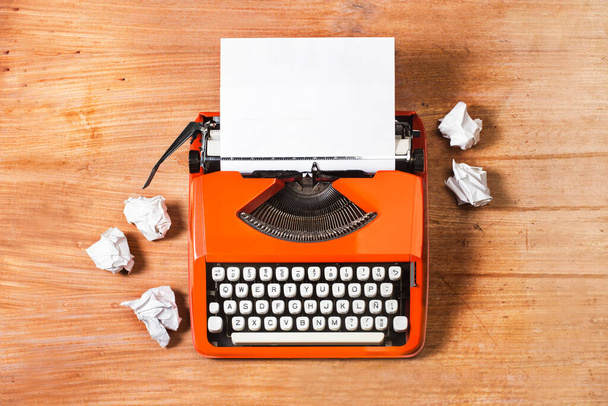 Eine Schreibmaschine mit einem Blatt Papier auf einem Holztisch in einer Draufsicht - Foto, Bild